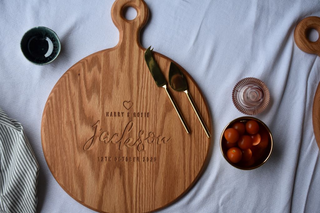 Engraved cheese board on a beautifully made table with tomatoes, fresh drinks and a cheese knife set